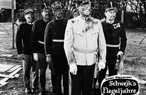 Fünf Soldaten in Uniformen stehen im Freien, einer ist schmutzig.