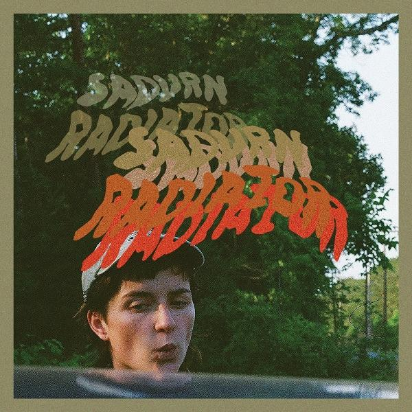 Junge mit Kappe und "SATURN RADIATOR" Schriftzug vor Bäumen.