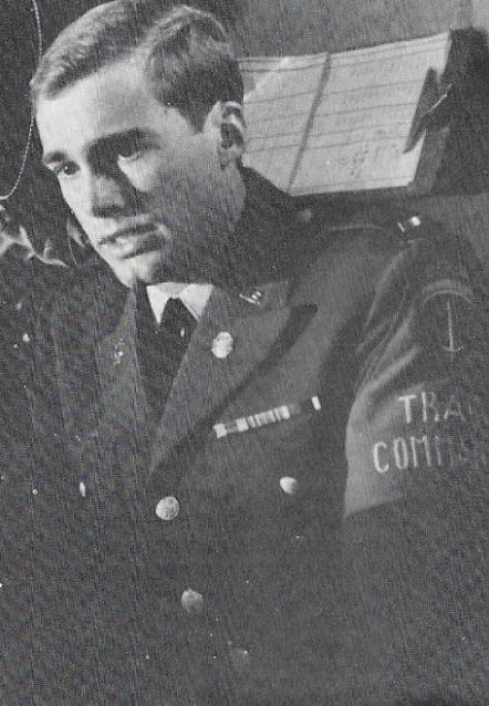 Mann in Uniform, Nahaufnahme, trägt Krawatte und Medaillen. Armbinde lautet 'TRACOM'.