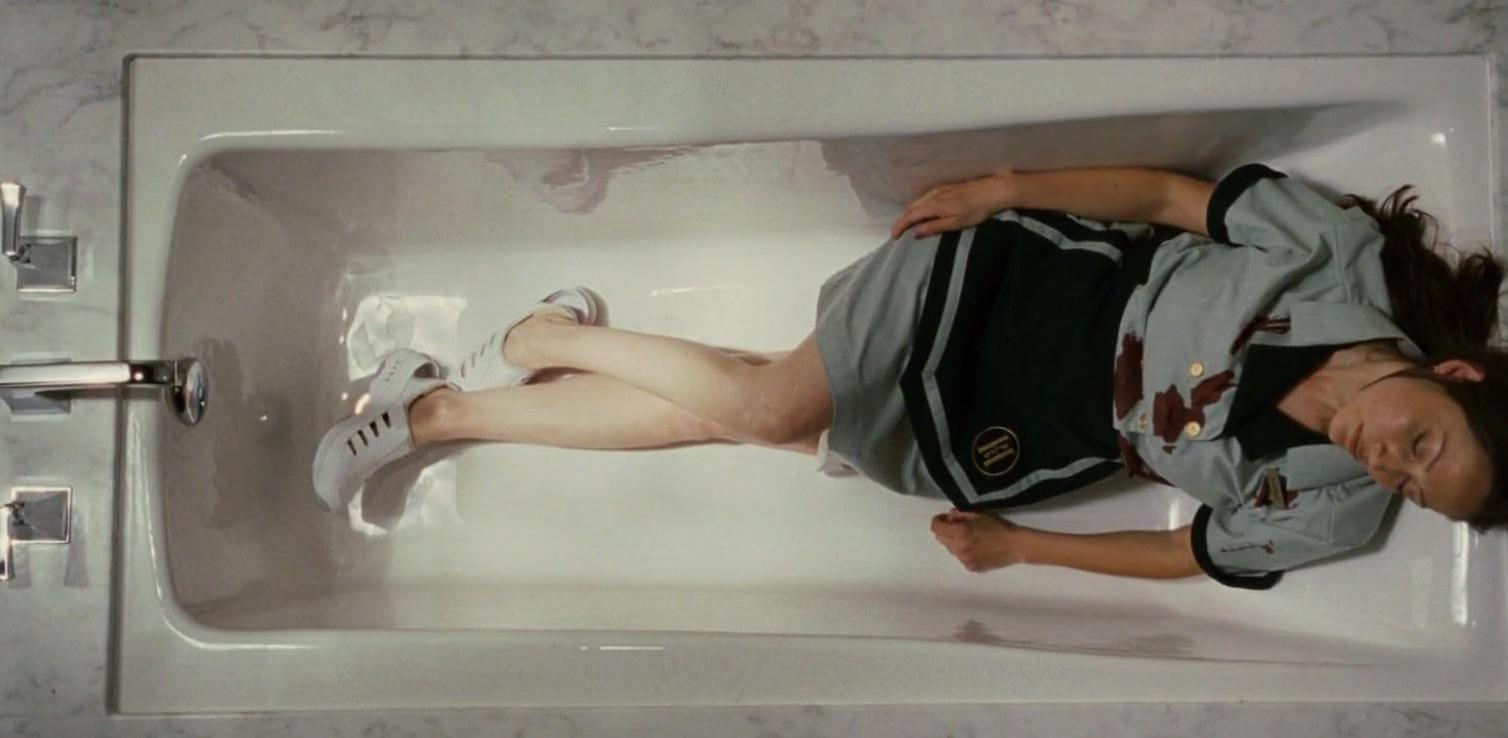 Eine Frau liegt in einer Badewanne, ihr Kopf ruht auf dem Rand, ihr Körper ist mit Wasser bedeckt.