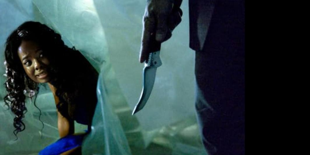 Eine Frau kauert vor einem Mann, der ein Messer hält.