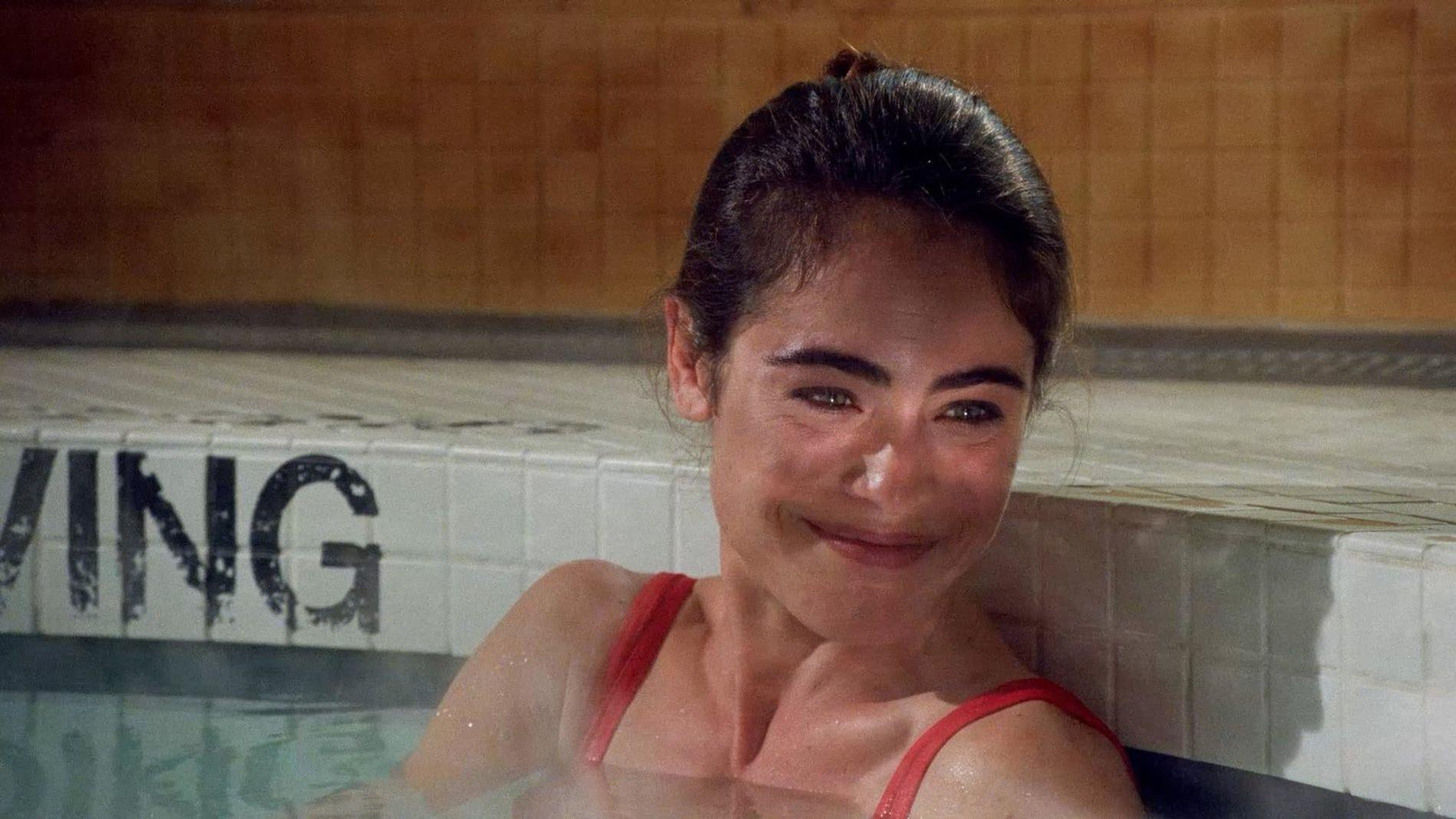 Frau in rotem Badeanzug lächelt in einem Pool mit Fliesenrand, auf dem 'VING' steht.