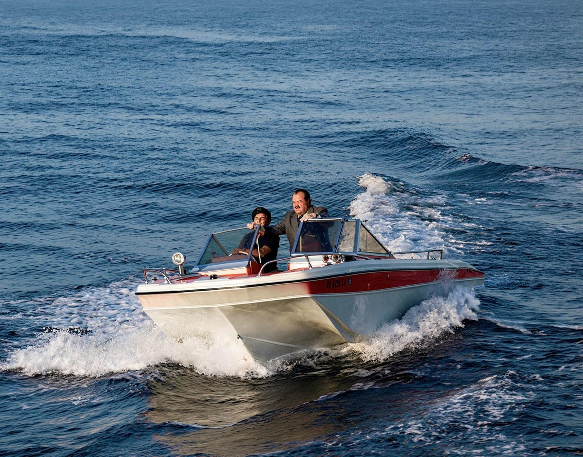 Zwei Männer in einem roten und weißen Schnellboot auf dem offenen Meer.