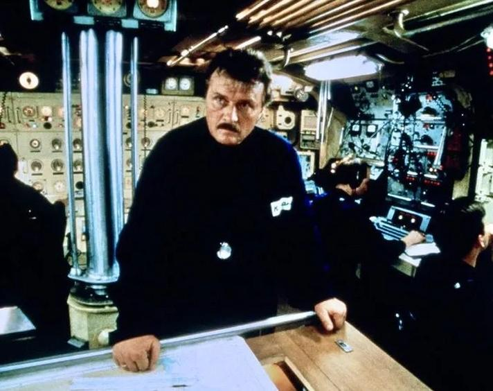 Männer in einem U-Boot-Kontrollraum mit Instrumenten und Monitoren.