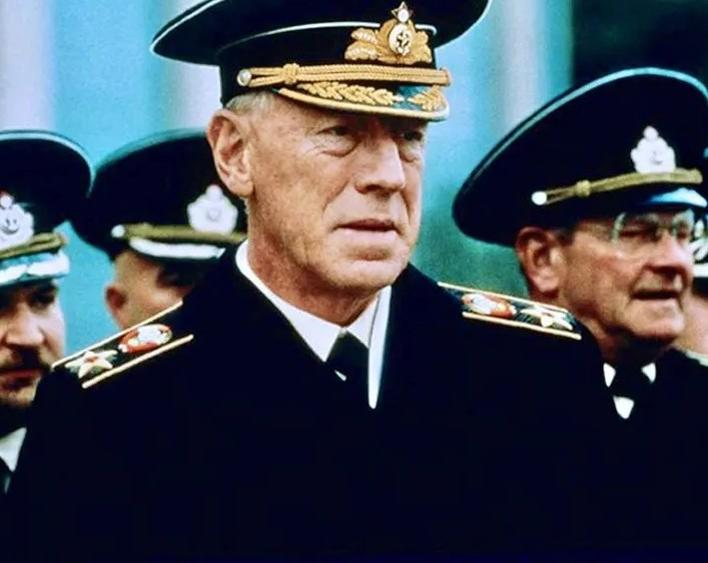 Älterer Mann in Uniform mit Auszeichnungen, blickt nach rechts. Andere Offiziere im Hintergrund.