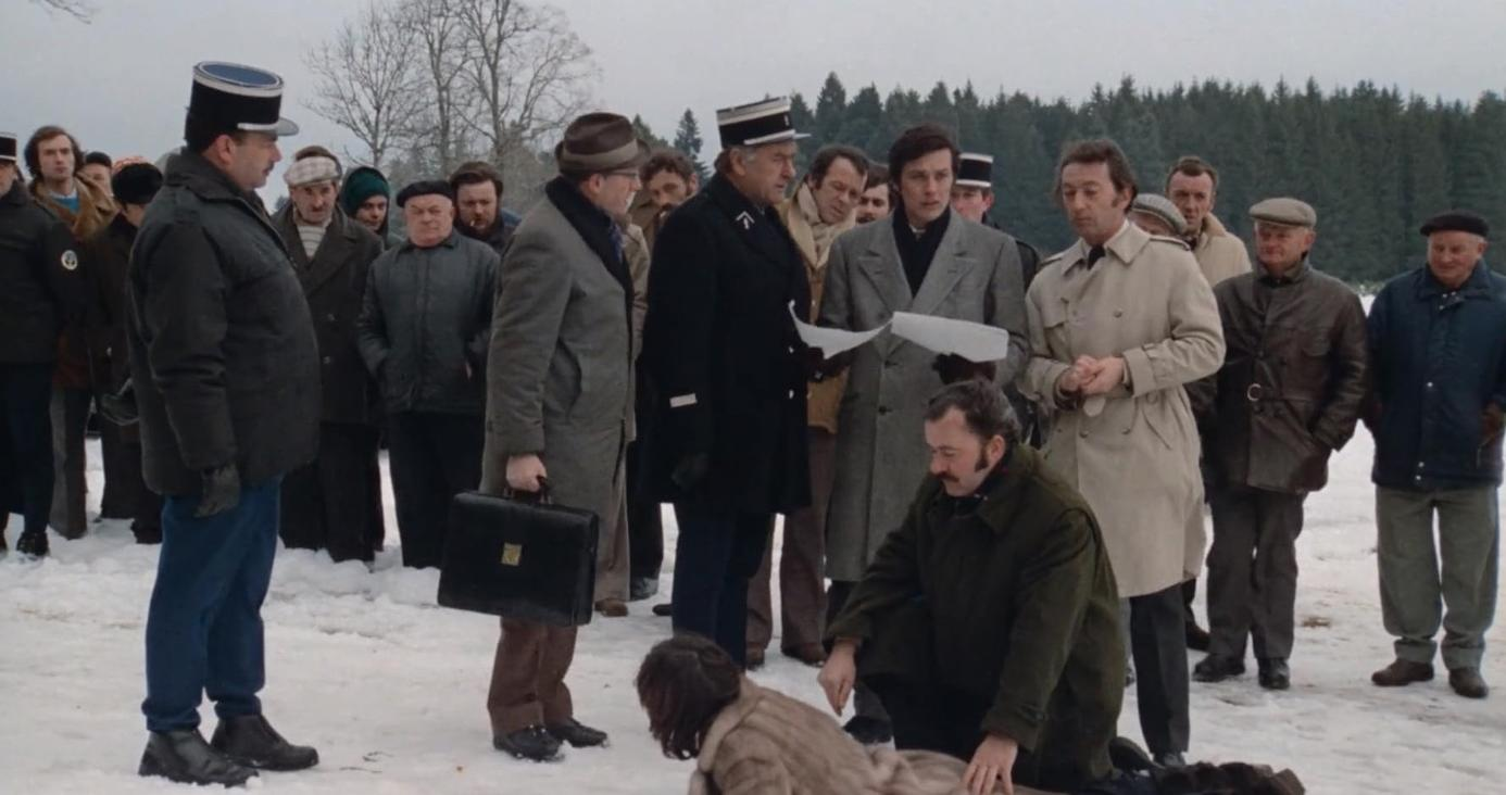 Eine Gruppe von Männern steht im Schnee, einige in Uniform, mit Bäumen im Hintergrund.