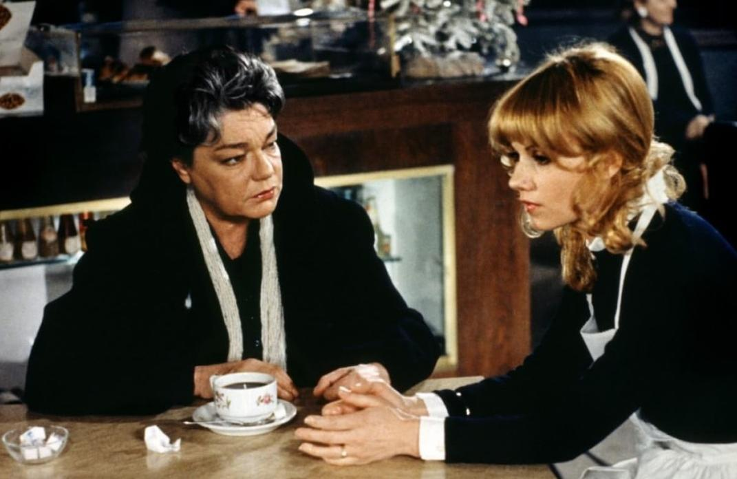 Zwei Frauen sitzen an einem Tisch mit einer Kaffeetasse und Zuckerwürfeln.