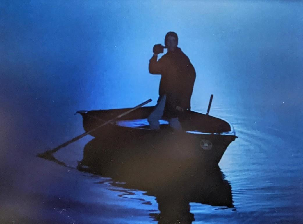 Mann in einem Boot, der in einem blauen Nebel trinkt.
