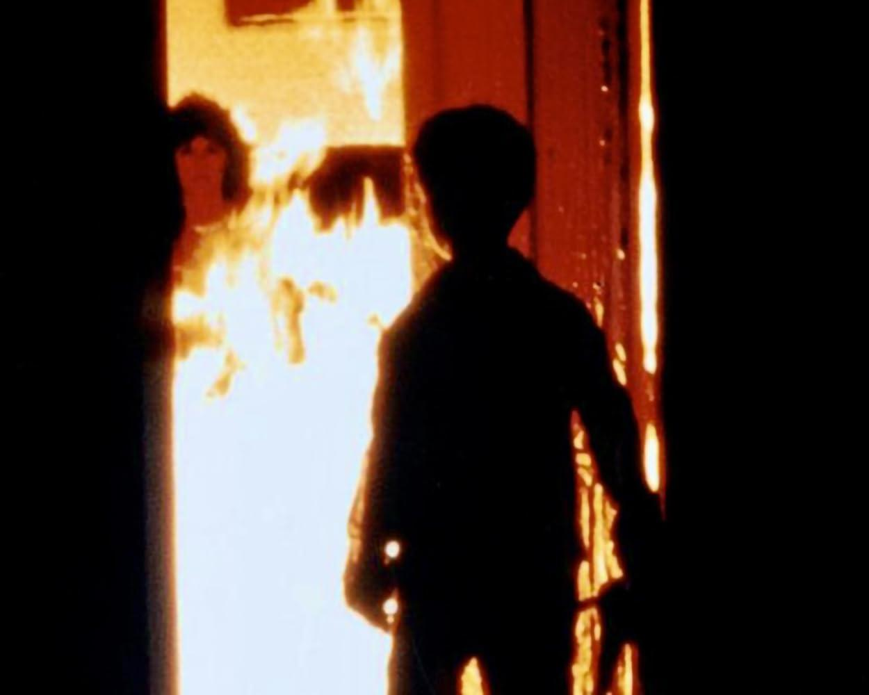 Silhouetten von Menschen in der Nähe eines hellen Feuers.