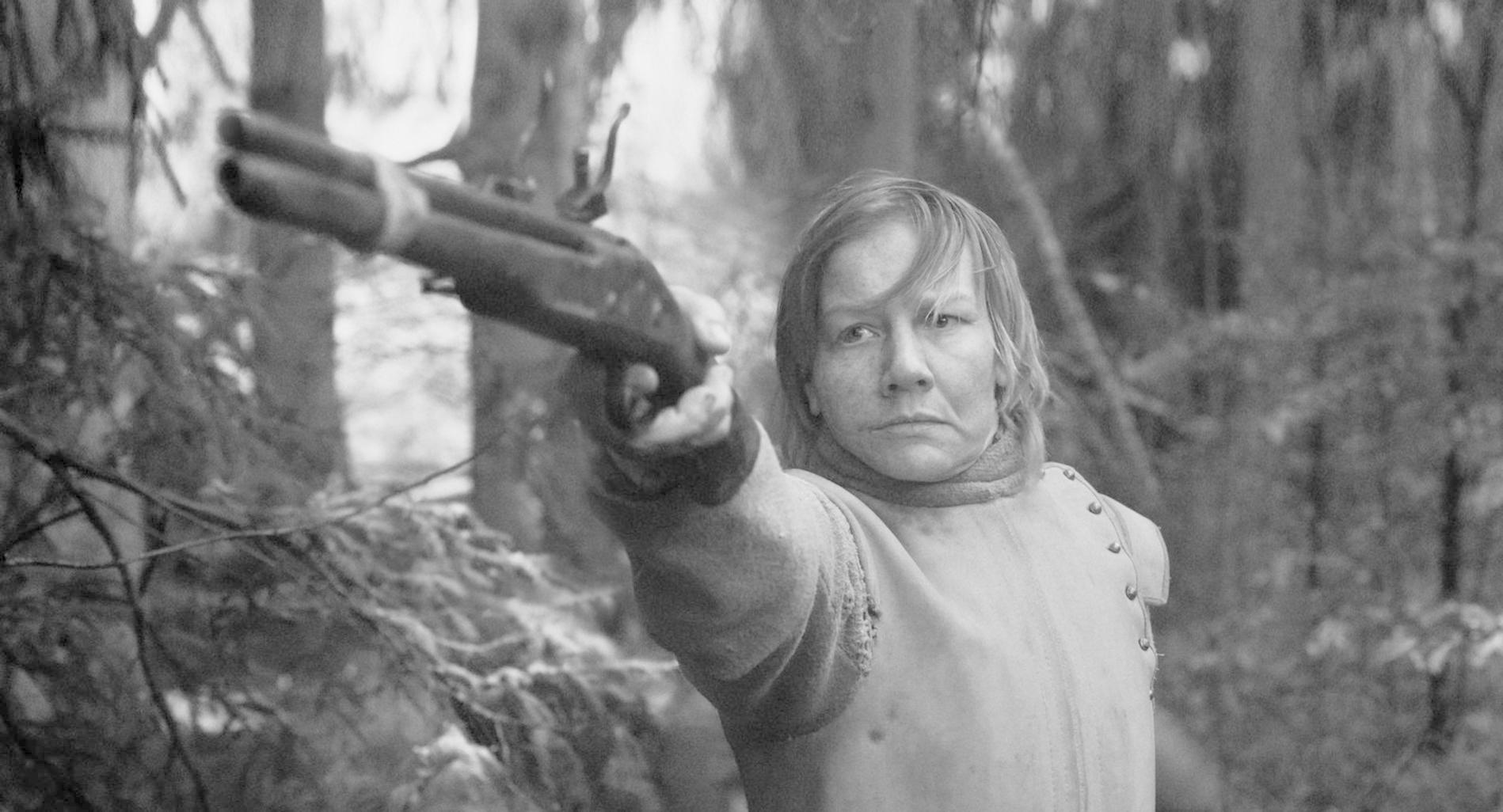 Eine Frau mit einem Gewehr im Wald.