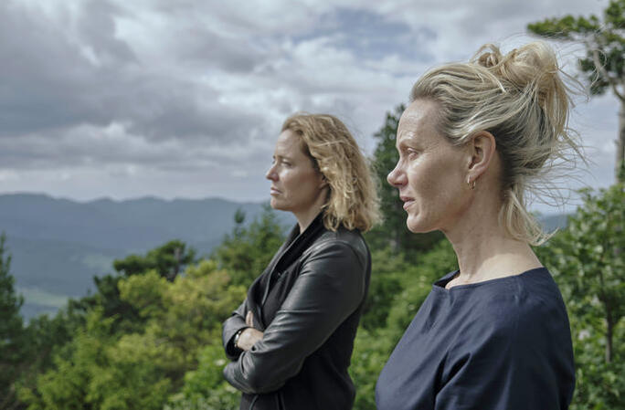 Zwei Frauen stehen im Freien mit Blick auf eine bewaldete Landschaft.