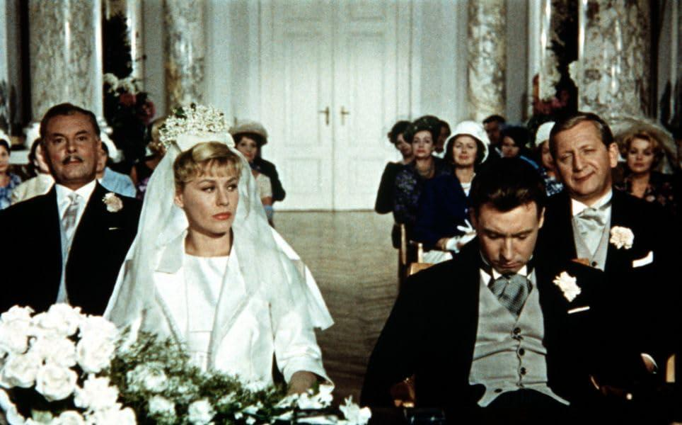 Hochzeitspartei in formeller Kleidung. Braut trägt Schleier und Krone. Bräutigam trägt Anzug.