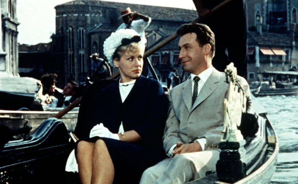 Ein Mann und eine Frau sitzen in einer Gondel in Venedig. Gebäude im Hintergrund.