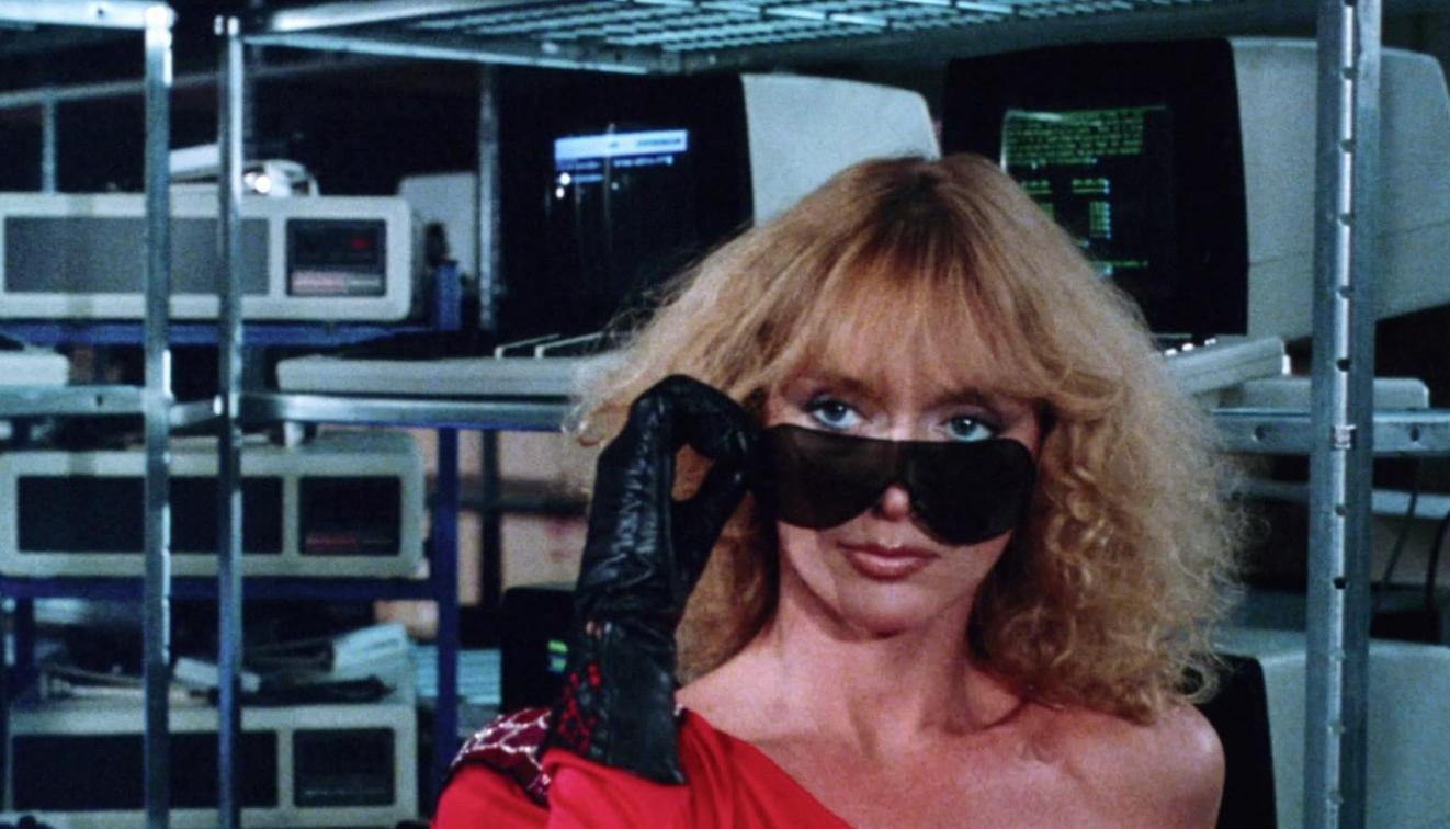 Frau mit blonden Haaren und Sonnenbrille vor Computern