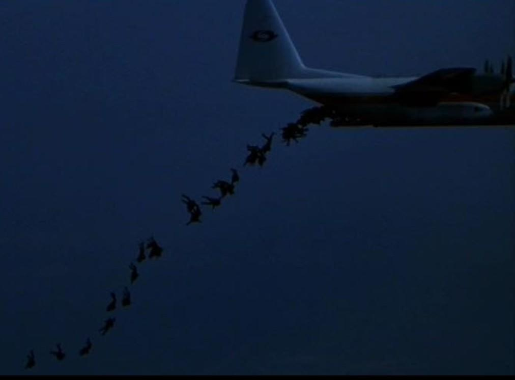 Ein Flugzeug wirft Fallschirmspringer in der Dämmerung ab.