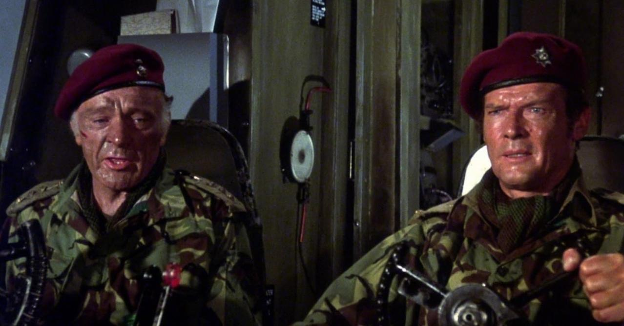 Zwei Männer in Tarnuniformen und roten Baretts sitzen im Cockpit.