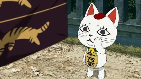 Eine weiße Katze mit rotem Fleck auf dem Kopf und einem goldenen Anhänger steht rechts.