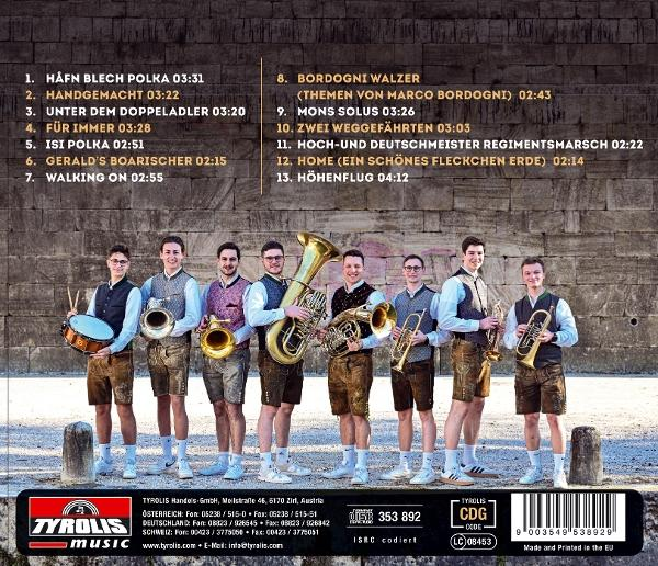 Neun Musiker in Tracht posieren mit Instrumenten vor einer Steinmauer.
