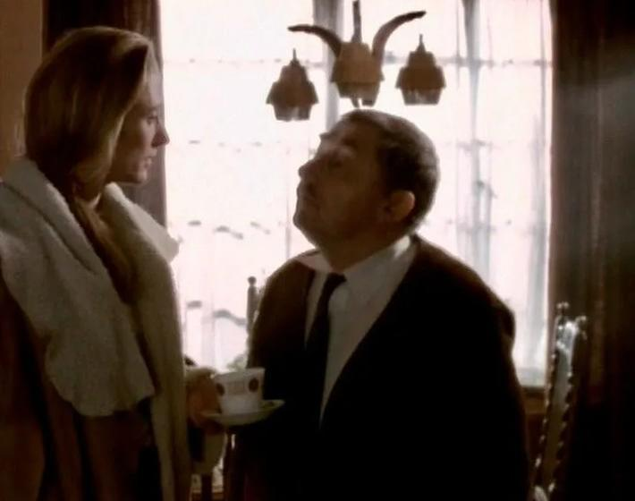 Eine Frau mit einem Schal spricht mit einem Mann, der eine Tasse hält.