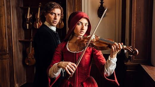 Ein Mann in schwarzer Kleidung und eine Frau in roter Kleidung mit Kapuze spielen Violine.