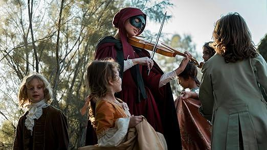 Eine maskierte Person spielt Violine für Kinder in historischen Kostümen im Freien.