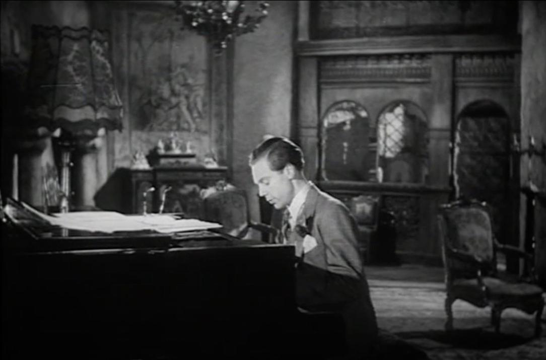 Ein Mann spielt Klavier in einem opulenten Raum mit Wandmalereien und einem Kronleuchter.