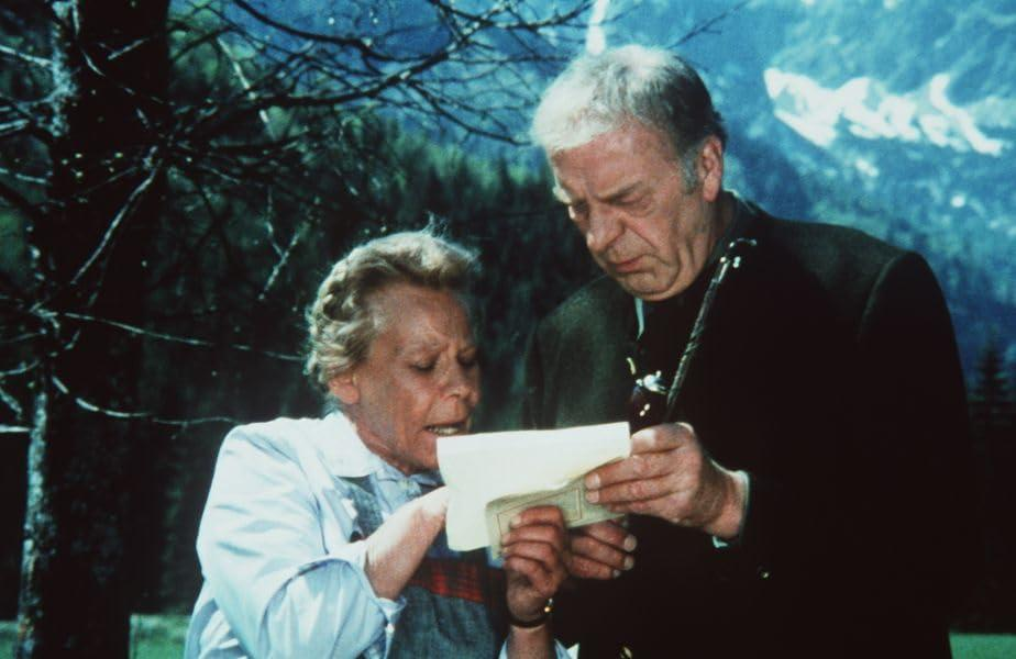 Ein älteres Paar liest gemeinsam einen Brief in den Bergen.