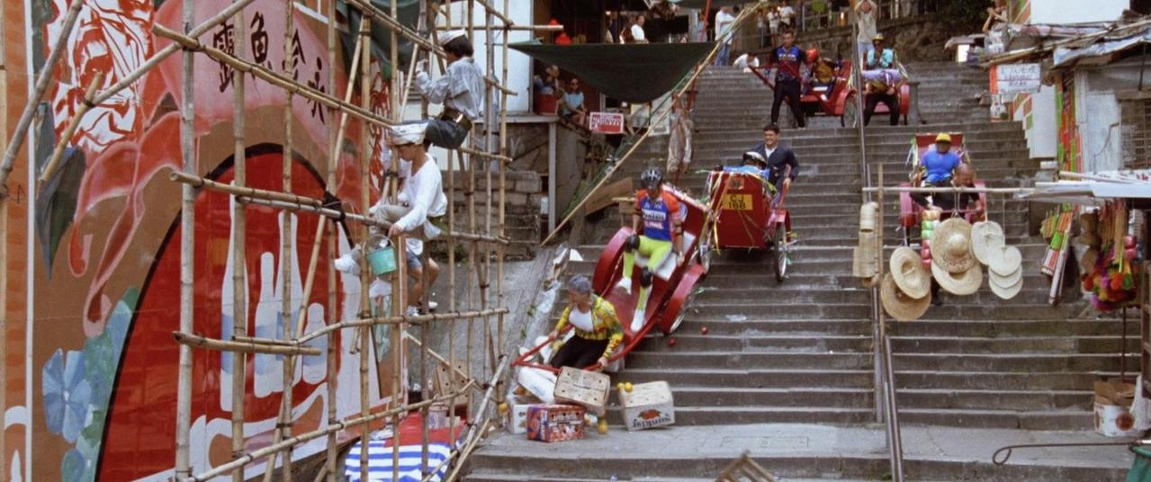 Eine Straßenszene mit vielen Menschen, die Treppen hinauf und hinunter gehen. Ein Mann fährt ein Rikscha.