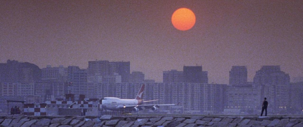 Flugzeug auf der Landebahn bei Sonnenuntergang mit Stadt im Hintergrund.