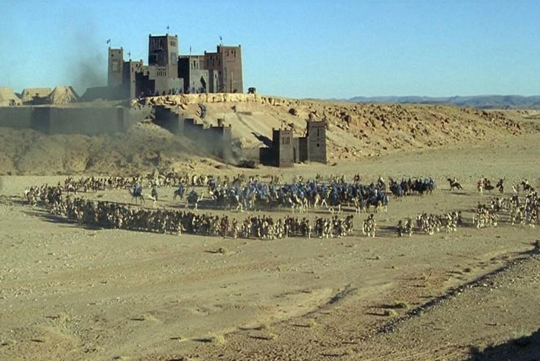 Wüstenszene mit einer großen Armee auf Kamelen und Pferden vor einer Festung.