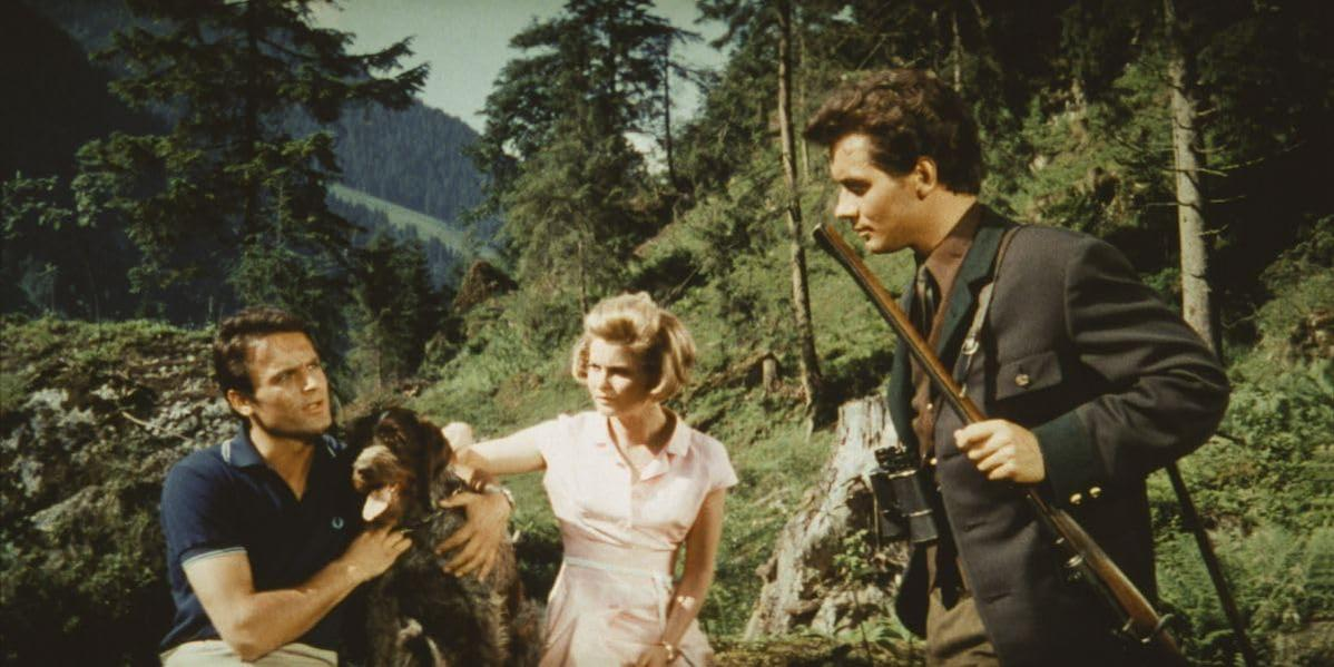 Mann mit Hund und Frau mit Gewehr im Wald.