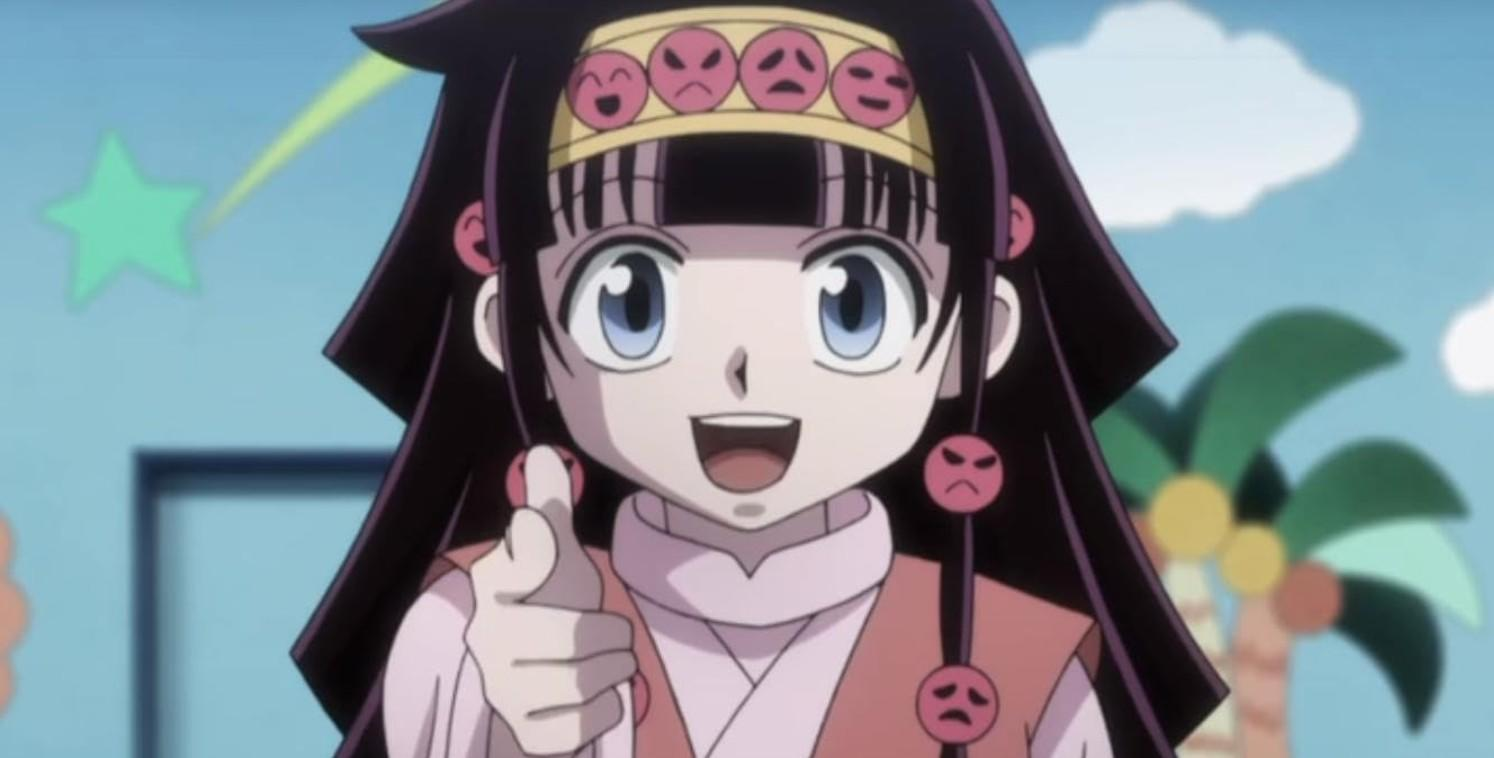 Anime-Mädchen mit dunklem Haar, blauen Augen und Stirnband mit Gesichtern. Zeigt mit dem Finger.