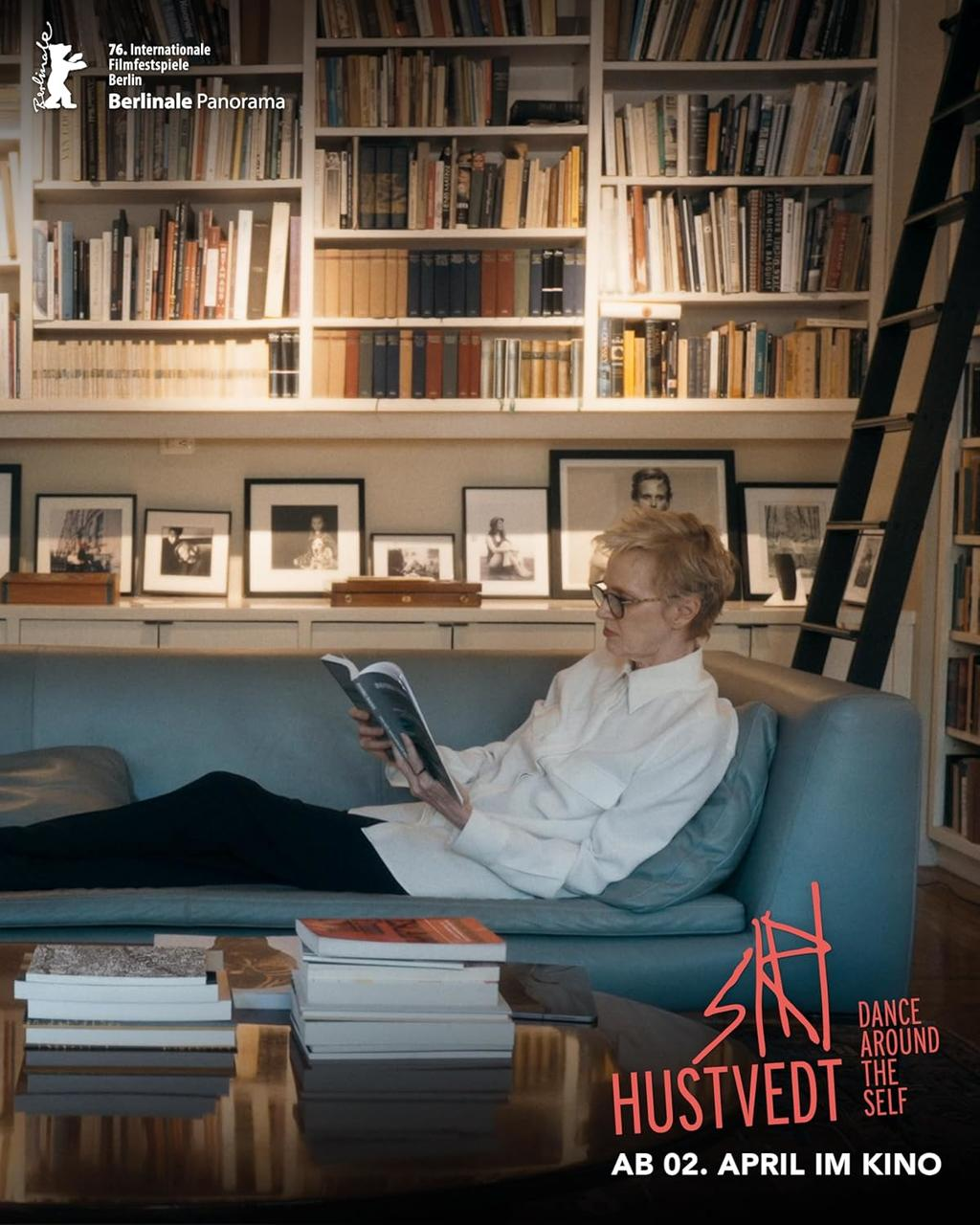 Eine Frau liest auf einem Sofa vor einem Bücherregal ein Buch.