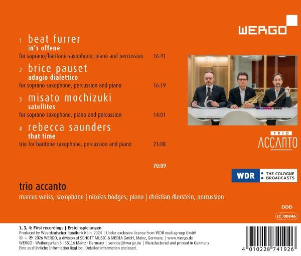Drei Männer sitzen an einem Tisch. Einer hält ein Saxophon, der andere Schlagzeugstöcke.