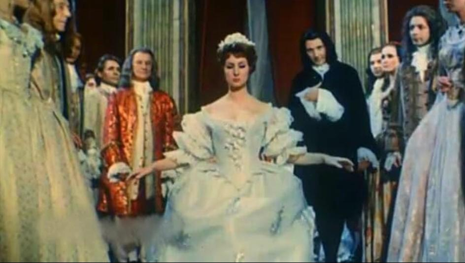 Eine Frau im weißen Kleid mit einer Krone steht im Mittelpunkt eines Hofes.