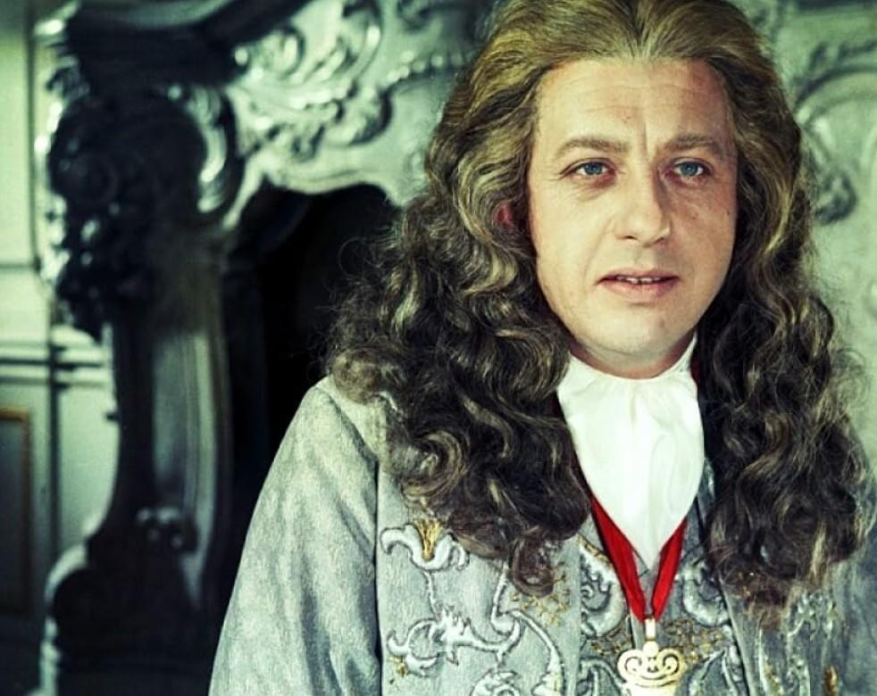 Mann mit langer, lockiger Perücke, in historischem Gewand und Medaillon.