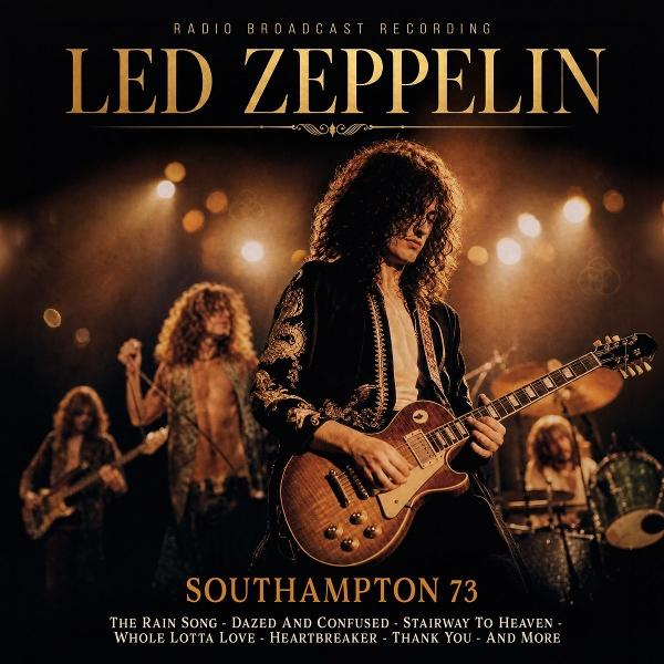 Led Zeppelin spielt auf einer Bühne, ein Gitarrist im Vordergrund, Bandmitglieder im Hintergrund.