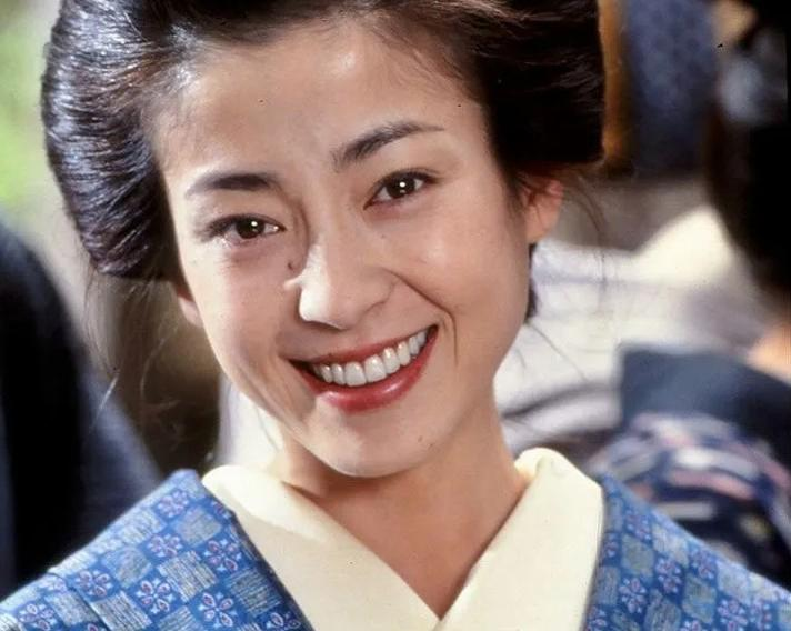 Nahaufnahme einer lächelnden Frau in Kimono mit blauem Muster.