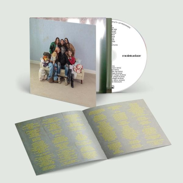 Eine Gruppe von Menschen sitzt auf einer Couch, umgeben von Teddybären. Eine CD liegt daneben.