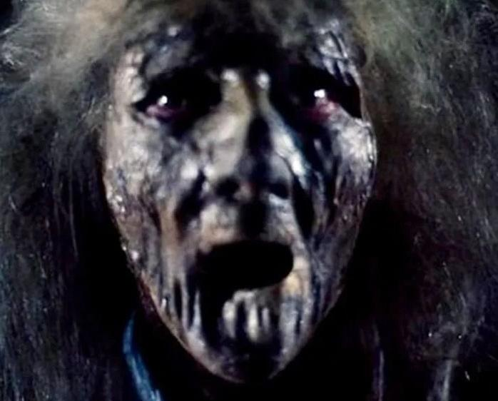 Nahaufnahme eines verrottenden Zombiegesichts mit dunklen, hohlen Augen und offenem Mund.