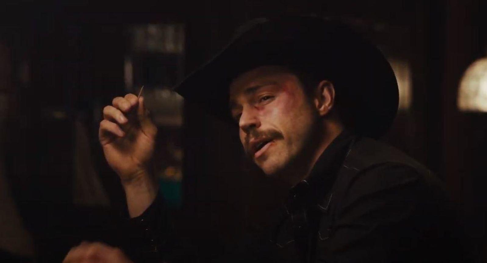 Ein Mann mit Cowboyhut und Schnurrbart, der eine Zahnstocher hält.