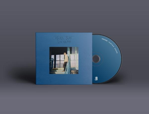 Ein Mann steht auf einer Treppe vor einem blauen CD-Cover und einer CD.