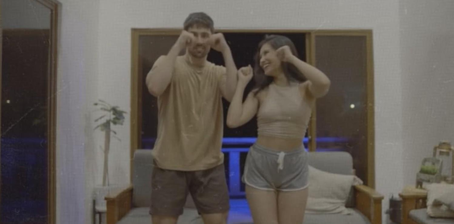 Ein Mann und eine Frau tanzen fröhlich in einem Wohnzimmer.