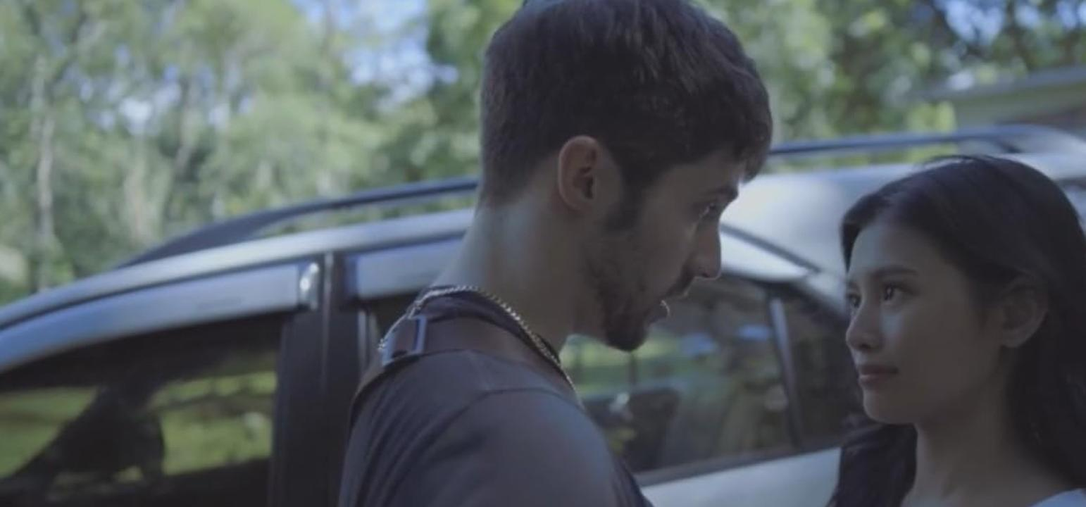 Ein Mann und eine Frau stehen neben einem Auto im Freien.