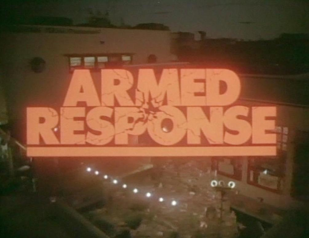 Orangefarbener Text „ARMED RESPONSE“ an einem Gebäude bei Nacht. Lichter unten.