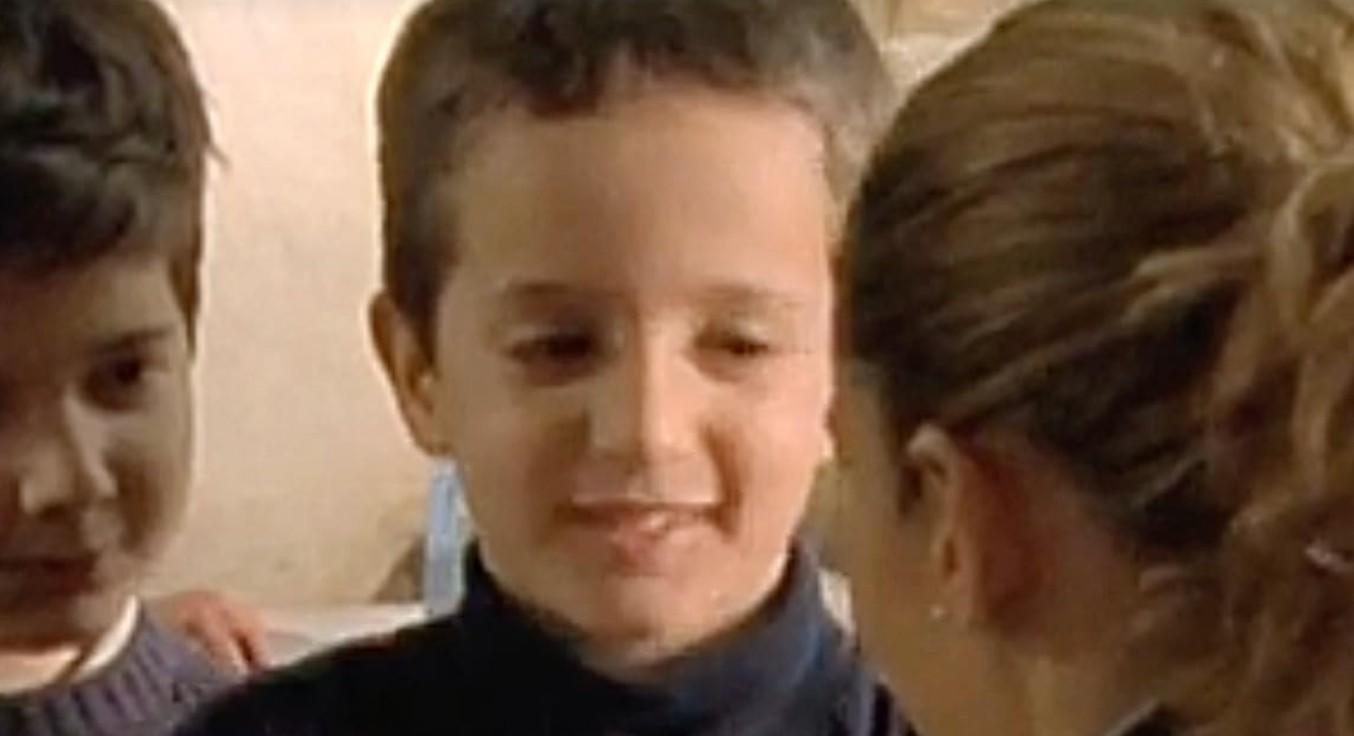 Drei Kinder im Vordergrund, ein Junge lächelt, die anderen sind unscharf.
