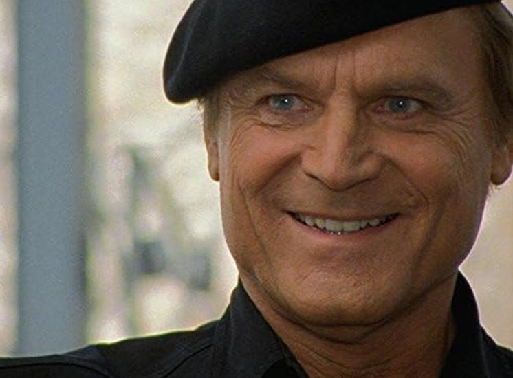 Ein Mann mit blauen Augen und schwarzem Barett lächelt.