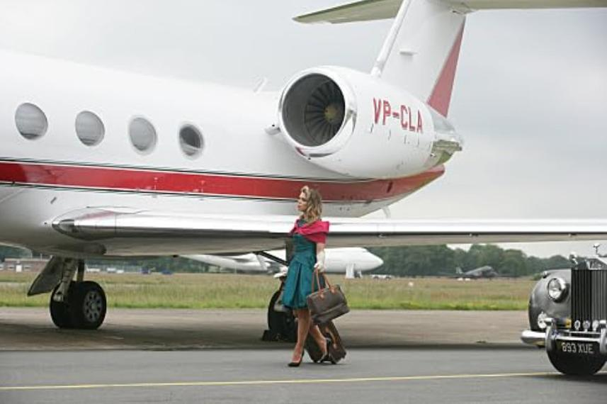 Eine Frau mit Gepäck steigt neben einem Privatflugzeug aus einem Auto.