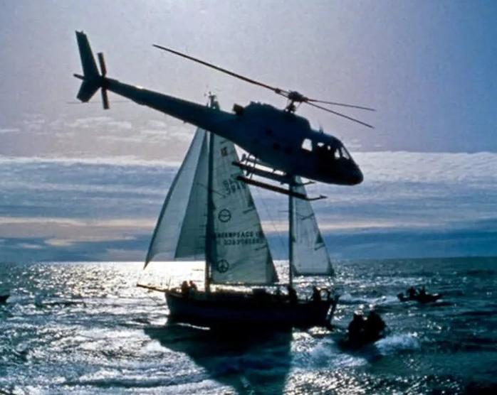 Hubschrauber schwebt über einem Segelboot auf dem Meer mit kleineren Booten in der Nähe.