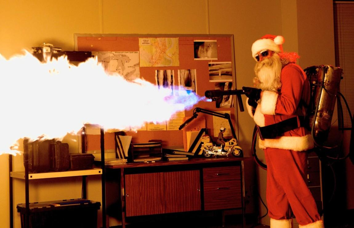 Weihnachtsmann mit Flammenwerfer feuert einen Strahl aus einem Gewehr ab.